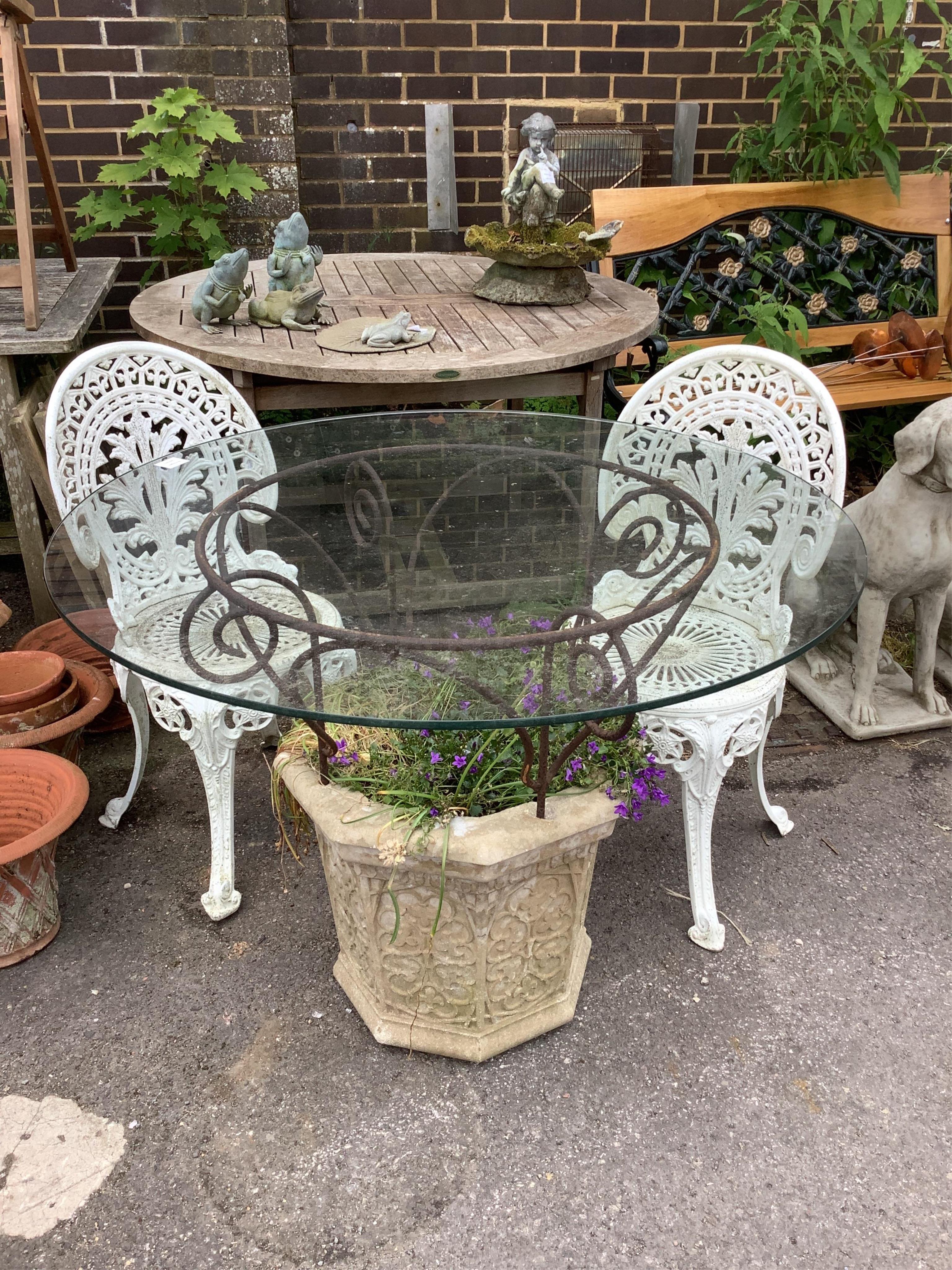A reconstituted stone and wrought iron glass top garden planter/table, diameter 100cm, height 77cm, together with a pair of aluminium chairs. Condition - good